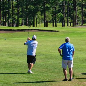 Two golfers chipping onto the green.