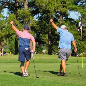 Two golfers celebrating on the green.